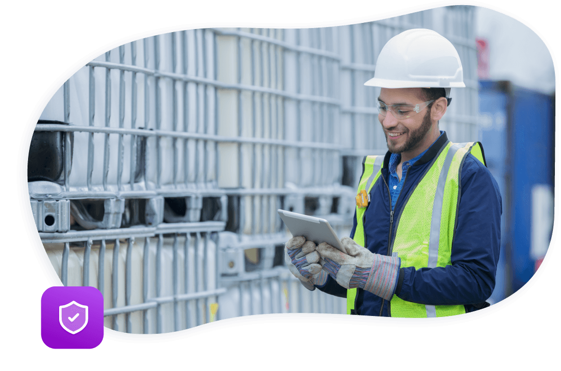 Man in a high visibility vest and safety helmet smiling while using a tablet device